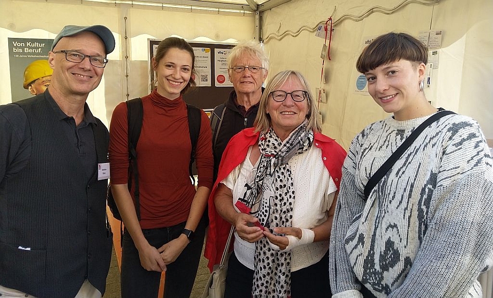 Foto: VHS 100 Jahr-Feier:  Besucherinnen und Besucher am Stand des Abendgymnasiums